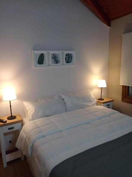 un dormitorio con una cama grande con dos luces sobre mesas en BE MAISON USHUAIA de Ushuaia