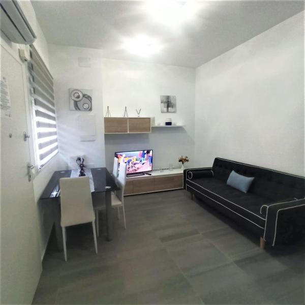 sala de estar con sofá, mesa y TV en LOFT MEDITERRÁNEO, en Málaga