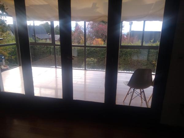 una ventana con vistas a un patio con una silla al aire libre en Chalet Céntrico en Barrio Residencial en San Carlos de Bariloche