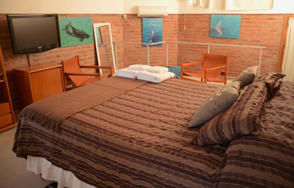 1 dormitorio con 1 cama, TV y sillas en Las Anémonas Sur en Puerto Madryn
