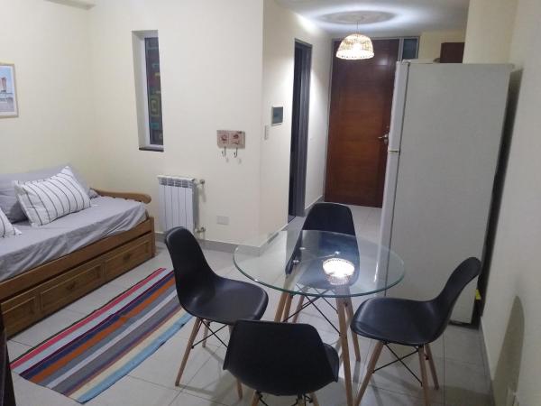 Habitación con mesa de cristal, sillas y cama en Departamento Paseo de los Poetas Premium en Salta