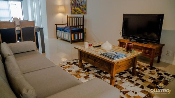 sala de estar con TV, sofá y mesa en Sobrado Praia do Mariscal com 3 dormitórios, en Bombinhas
