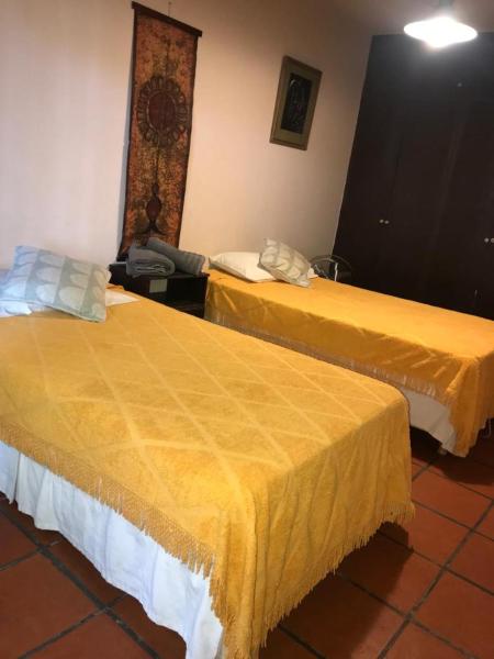 2 camas en una habitación de hotel con sábanas amarillas en Casa amplia en Godoy Cruz en Mendoza