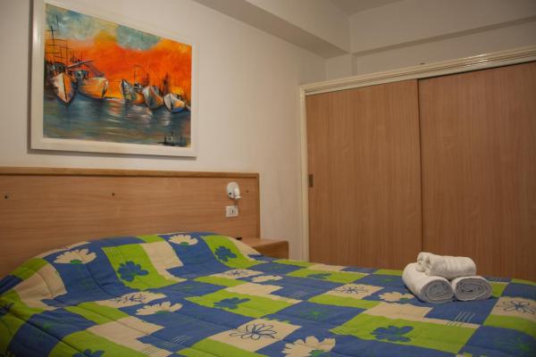 1 dormitorio con 1 cama colorida y toallas. en Alma Departamentos de Mar en Ostende