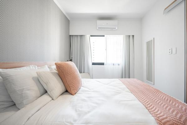 1 dormitorio blanco con 1 cama blanca grande con almohadas en Apto moderno com varanda e vaga - Itaim Bibi, en São Paulo