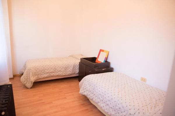 Un dormitorio con 2 camas y una mesa con una foto. en Habitación privada en Nuestra Casa del Pueblo en Esquel