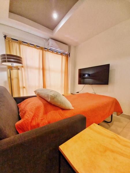 1 dormitorio con 1 cama con manta naranja y sofá en AltoAndino - Excelente Ubicación - p/4 c/cochera en Salta