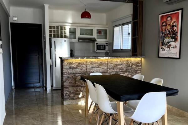 cocina con mesa negra y sillas blancas en Departamento 3 ambientes - Amarras Pinamar en Pinamar