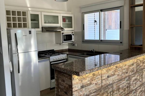 una cocina con refrigerador y electrodomésticos de acero inoxidable en Departamento 3 ambientes - Amarras Pinamar en Pinamar