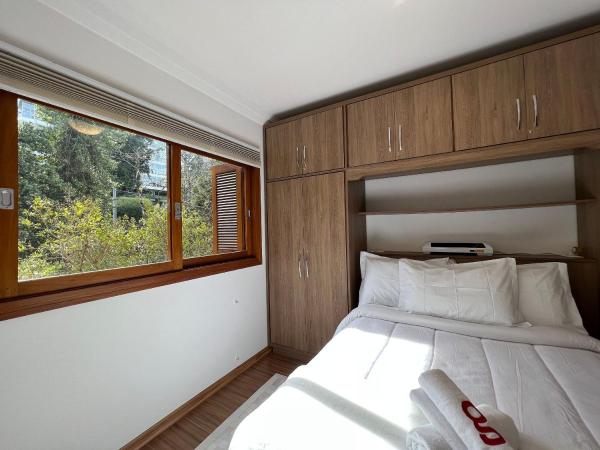 1 dormitorio con cama y ventana grande en Vista do Quilombo 204B - Apartamento no Centro de Gramado, en Gramado