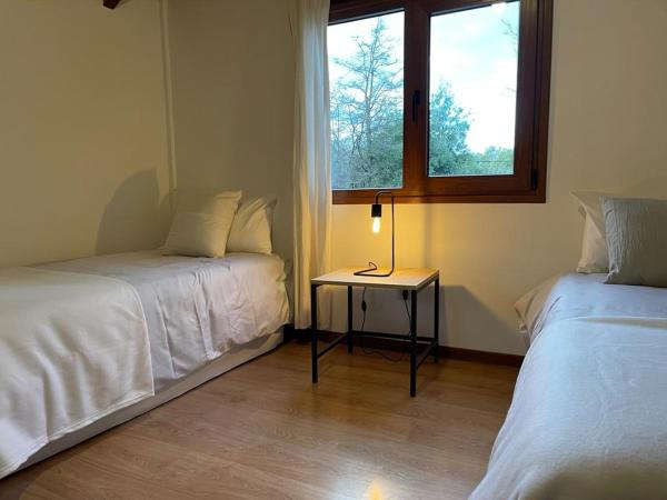 Habitación con 2 camas y mesa con ventana en Bella casa cercana al centro de ski y playas. en San Carlos de Bariloche