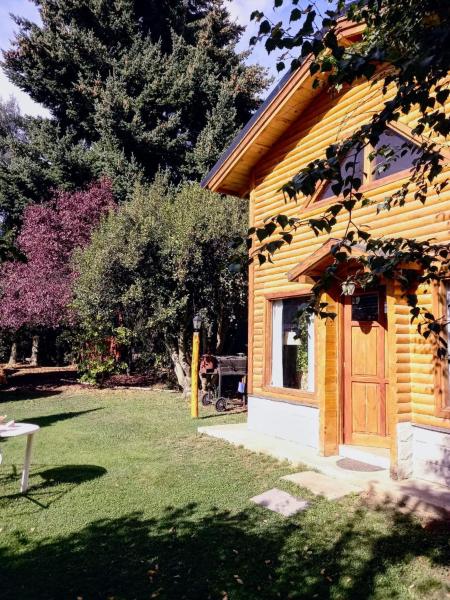 una casa de madera con una puerta en un patio en Cabañas Villa Centauro en San Carlos de Bariloche