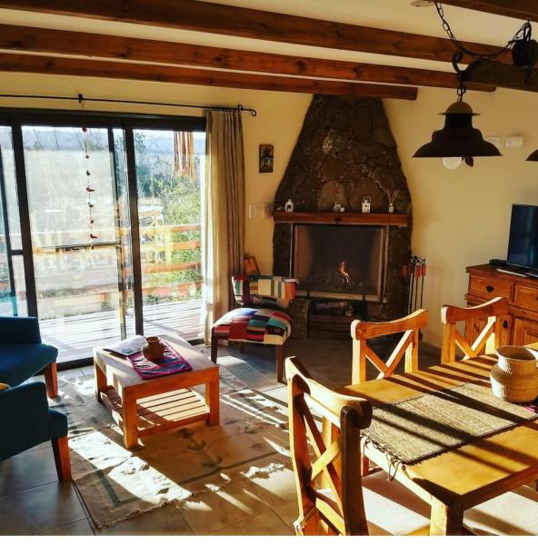 sala de estar con mesa y chimenea en Terrazas de Piedra, en Santa Rosa de Calamuchita