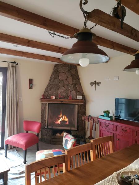 sala de estar con chimenea, mesa y sillas en Terrazas de Piedra, en Santa Rosa de Calamuchita