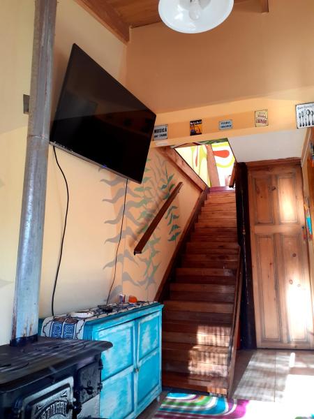 sala de estar con TV en la pared y escaleras en Sauce Grande en Tandil
