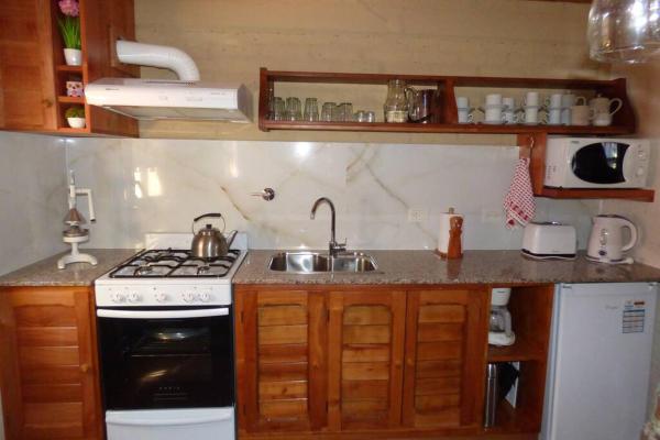 una pequeña cocina con fogones y fregadero en Confortable cabaña en zona céntrica de la ciudad. en San Martín de los Andes
