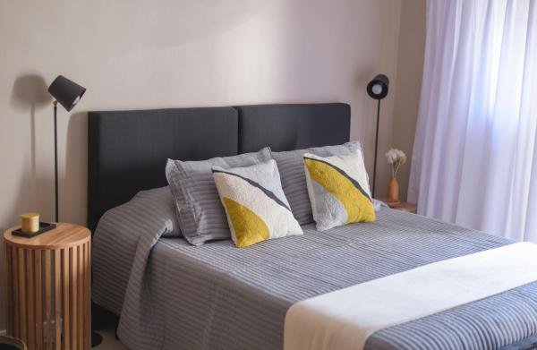 1 dormitorio con 1 cama con almohadas amarillas y grises en Chic Studio en Retiro en Buenos Aires