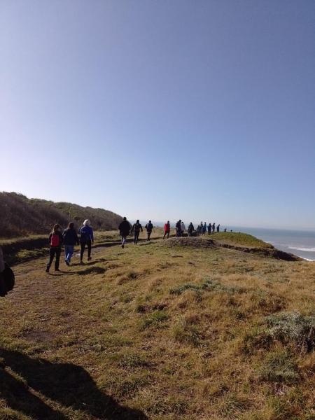 un grupo de personas caminando en una colina cerca del océano en Acantilados Surf Ranch en Mar del Plata