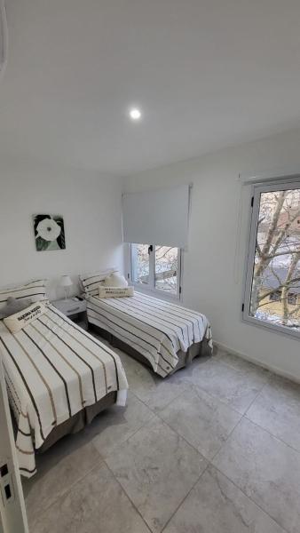 2 camas en una habitación blanca con ventana en Duplex Sol la Perla en Mar del Plata