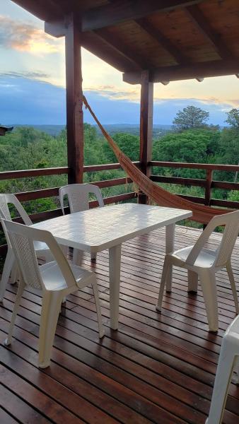una mesa blanca y sillas en una terraza de madera en Terrazas de Piedra, en Santa Rosa de Calamuchita