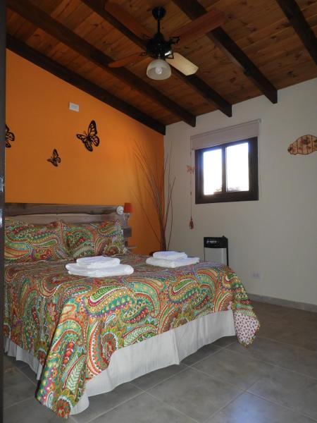 1 dormitorio con 1 cama con mariposas en la pared en Terrazas de Piedra, en Santa Rosa de Calamuchita