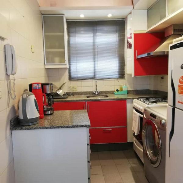 cocina con armarios rojos y lavadora en Cozy apartment in the heart of Cañitas en Buenos Aires