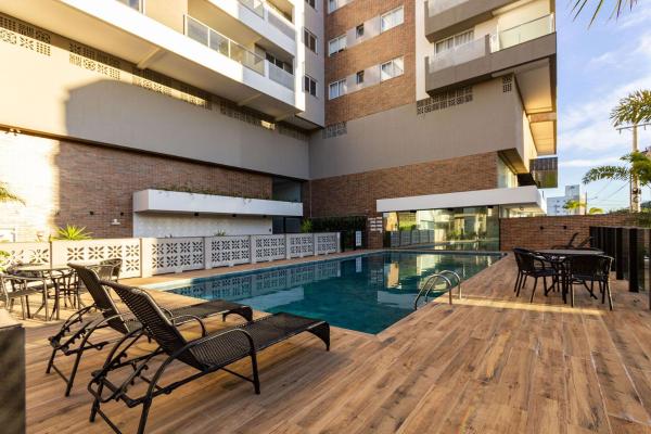 un edificio con piscina, mesas y sillas en Terrazzo Club Residence 407-B - Apartamento em Bombas - Edifício com Jacuzzi - Piscina - Quadra Poliesportiva, en Bombinhas