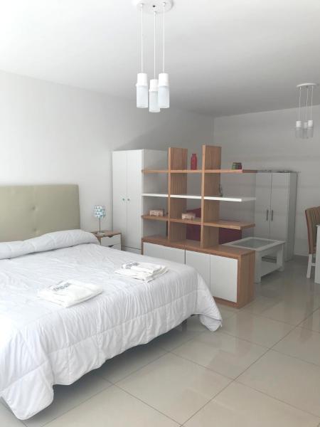 1 dormitorio con cama blanca y armario de madera en Departamento en Recoleta - Con pileta, parilla, gym - Piso 2 en Buenos Aires