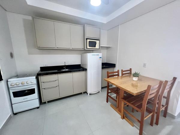 cocina con mesa y refrigerador blanca en Sal De Mariscal 09, en Bombinhas
