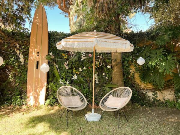 dos sillas y una sombrilla junto a una tabla de surf en Luxury pool villa at Malaga's best beach!, en Málaga