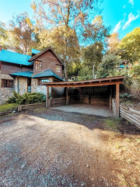 una casa grande con un granero y un camino de entrada en Cabaña La Tranquila en San Martín de los Andes