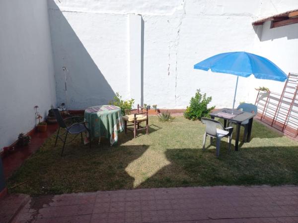 un patio con una mesa y una sombrilla azul en Habitacion privada en hermosa casa centrica de Ciudad en Mendoza