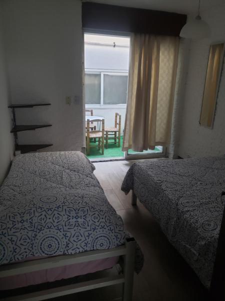 1 dormitorio con 2 camas y ventana con mesa en Departamento ubicadisimo calle Chile con estacionamiento incluido capital Mendoza3 centro en Mendoza
