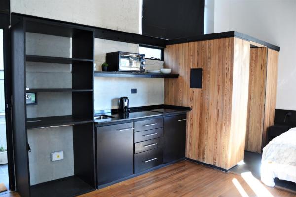 cocina con armarios negros y lavabo en una habitación en Departamentos Boulevard Caseros en Buenos Aires