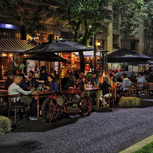 un grupo de personas sentadas en mesas en un restaurante por la noche en Departamentos Boulevard Caseros en Buenos Aires