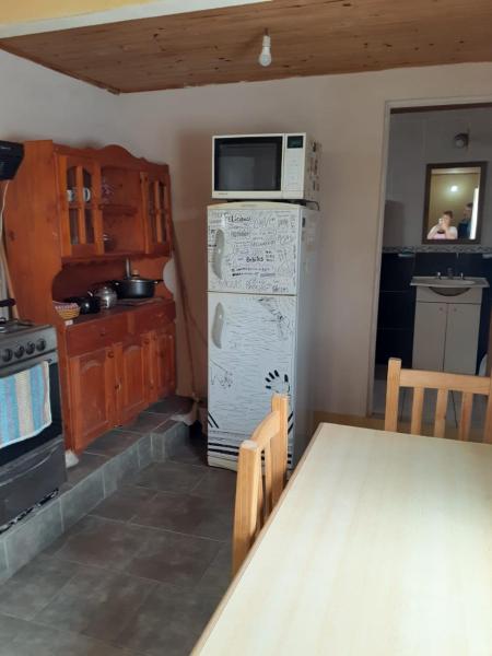 y cocina con mesa, microondas y refrigerador. en Departamento céntrico completo en Gualeguaychú