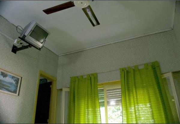 una habitación con televisión y una ventana con cortinas amarillas en el Hotel Danubio de Villa Gesell