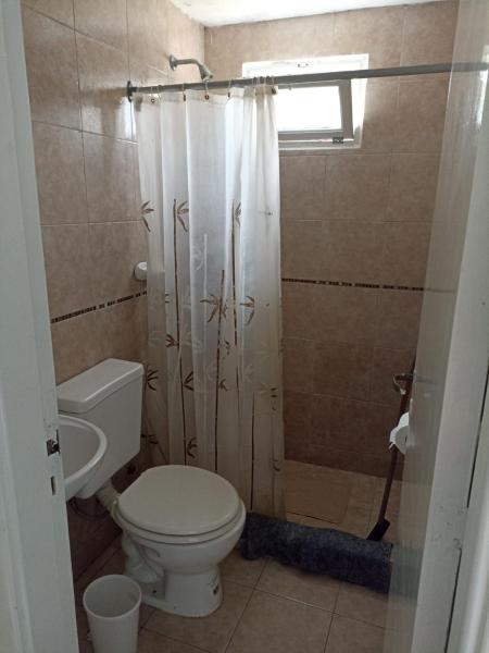 un baño con aseo y cortina de ducha en Bariloche en Villa Gesell
