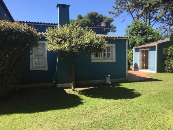 una casa verde con un árbol en el patio en casa azul en Villa Gesell
