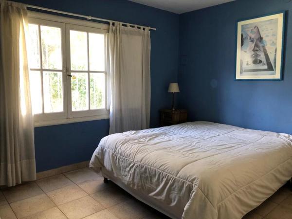 Dormitorio azul con cama y ventana en casa azul en Villa Gesell
