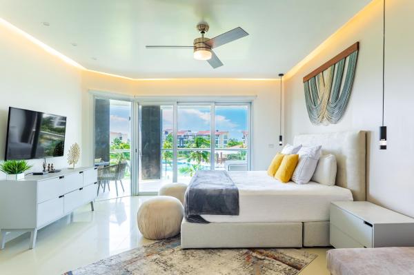 Habitación blanca con cama y TV en Casa Brisas apts, en Playa del Carmen