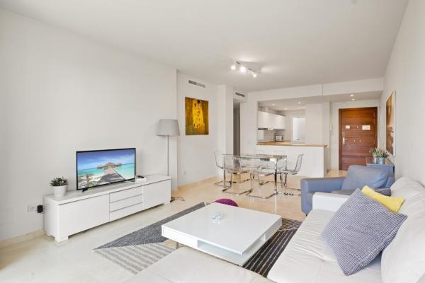 sala de estar con sofá blanco y TV en Stunning blue lagoon apartment in Estepona M12, en Estepona