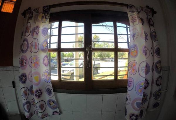 una ventana con cortinas en una cocina con vistas en Cabaña El Jacarandá, a 200 m. del mar en Puerto Madryn