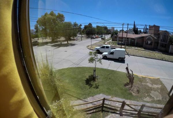 una vista desde una ventana de una calle con un camión blanco en Cabaña El Jacarandá, a 200 m. del mar en Puerto Madryn