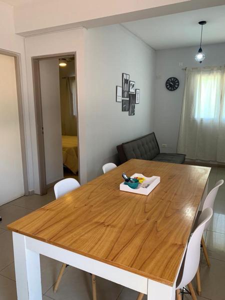 una mesa de madera con sillas blancas y una tabla de cortar en Andino Apartaments Rental Rivadavia en San Juan