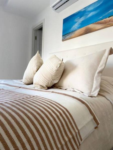 1 cama con almohadas blancas y una pintura en la pared en B Excepcional monoambiente en Mar del Plata a metros del mar en Mar del Plata