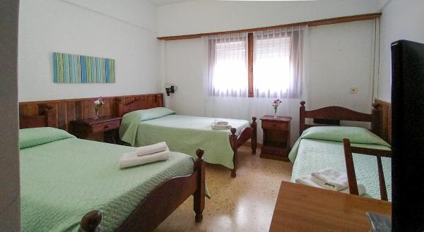 Habitación con 3 camas verdes y TV. en Hotel Meson en Pinamar