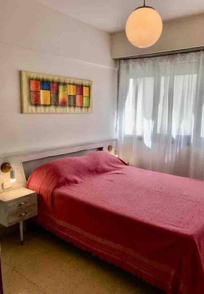 1 dormitorio con cama roja y ventana en Departamento con inmejorable ubicación en Mardel en Mar del Plata