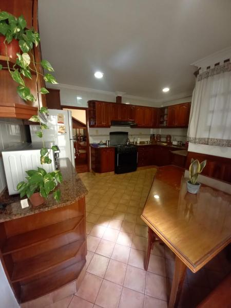 una cocina con armarios de madera y una mesa. en Casa La Linda de la Virrey en Salta