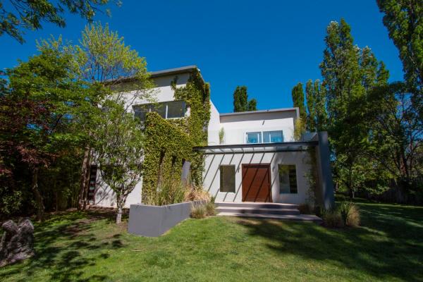 una casa blanca con una puerta marrón en un patio en La Escondida en Mendoza
